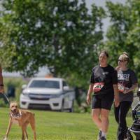 A racer walking her dog while a group with a stroller follows behind her.